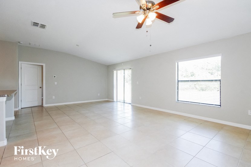 A spacious room with a ceiling fan and a window with blinds.