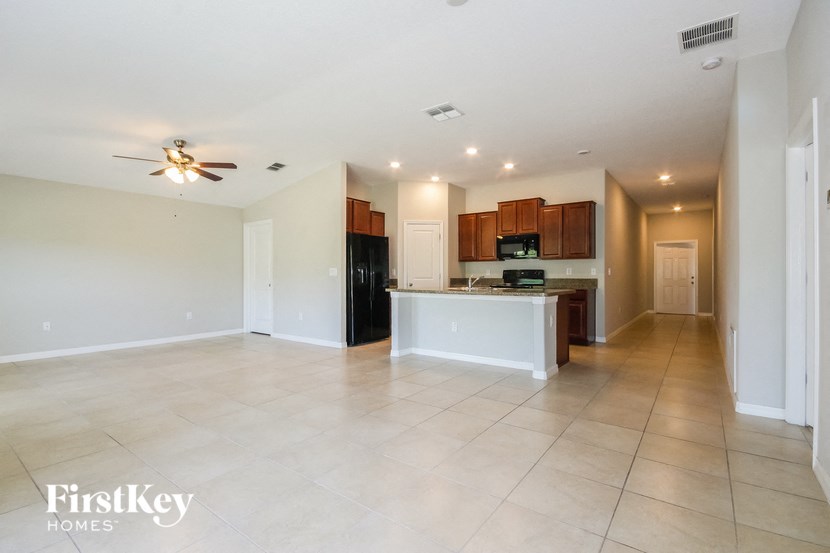 A spacious living room with a kitchen area in the background.