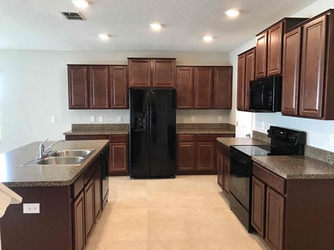 A kitchen with brown cabinets and black appliances.