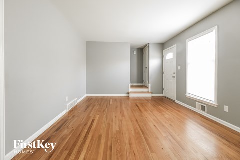a living room with wood flooring and a door to a hallway