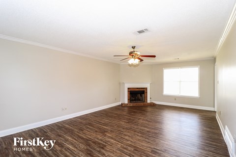 A spacious room with a fireplace and a ceiling fan.