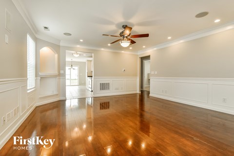 A spacious room with wooden floors and a ceiling fan.