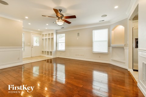 A spacious room with wooden floors and a ceiling fan.