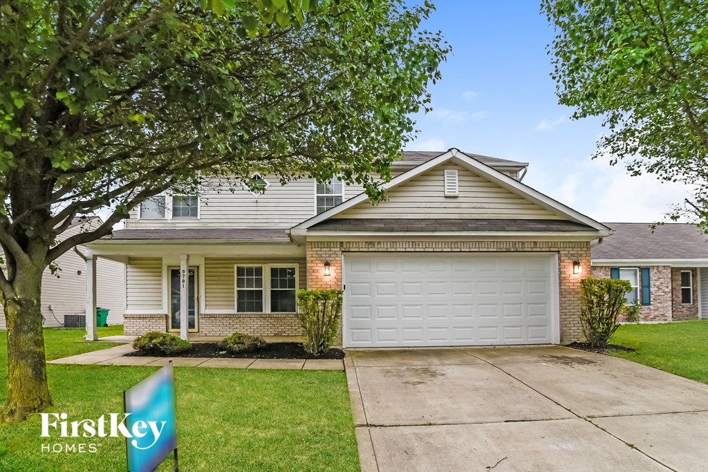a home with a white garage door and a tree