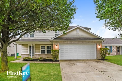a home with a white garage door and a tree