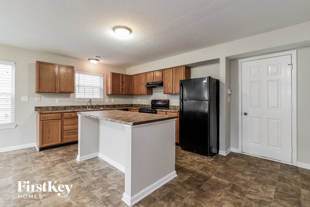 a kitchen with an island and a black refrigerator