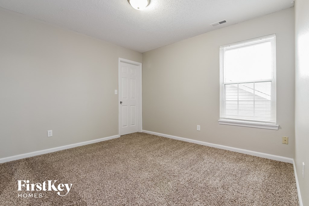 a bedroom with carpet and a window and a door