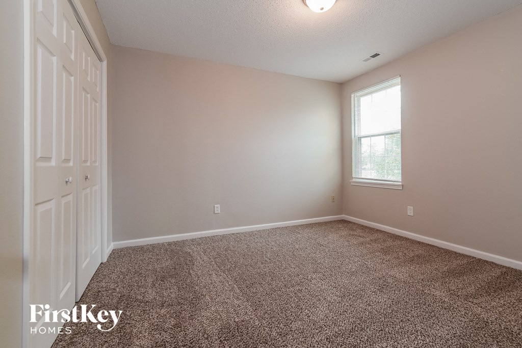 the living room of an empty house with carpet and a window