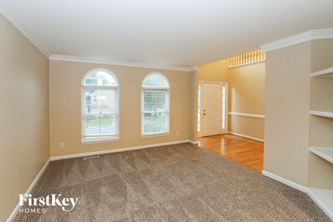 A spacious room with a carpeted floor and two arched windows.