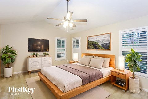 A bedroom with a bed, dresser, and ceiling fan.