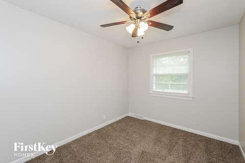 a bedroom with a ceiling fan and a carpet
