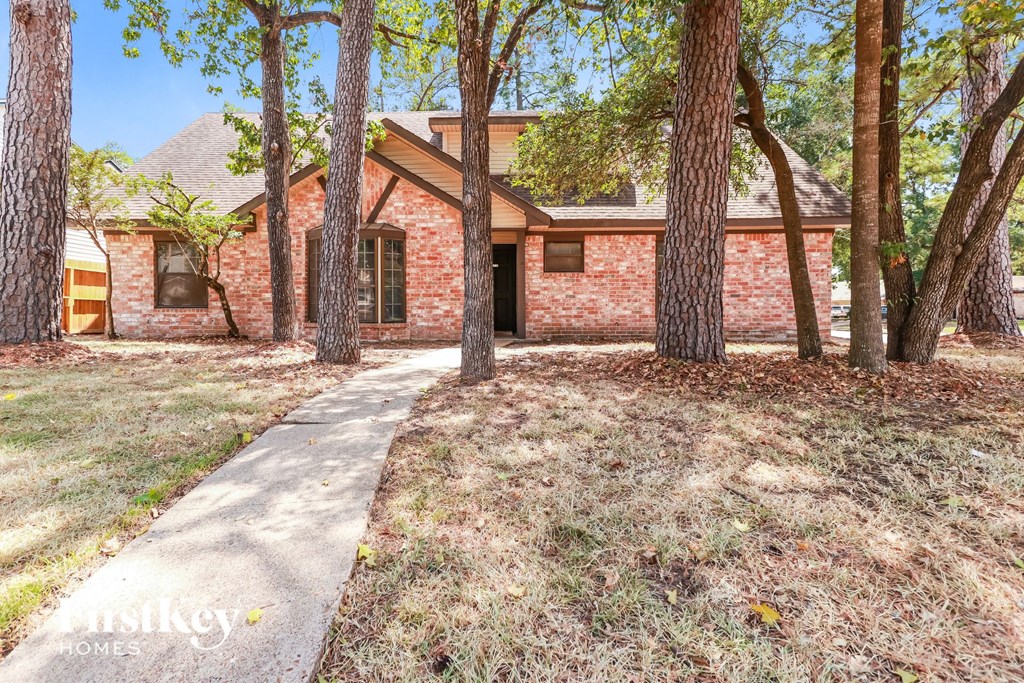 a brick house with a sidewalk and trees