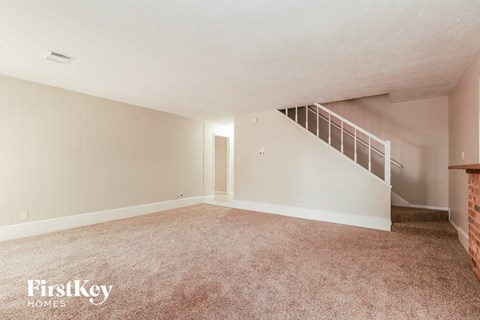 a living room with carpet and a staircase
