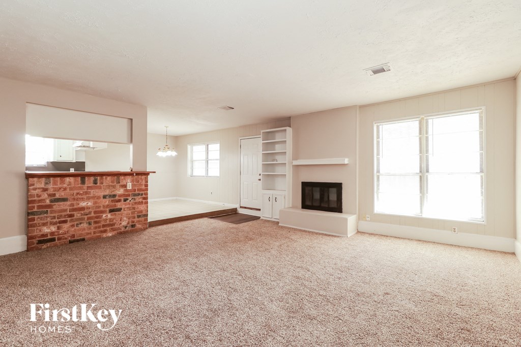 a living room with a brick fireplace and a carpeted floor