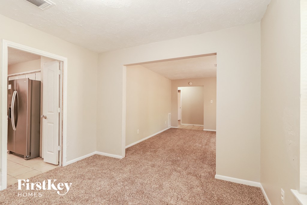 a living room with a refrigerator and a door into a hallway