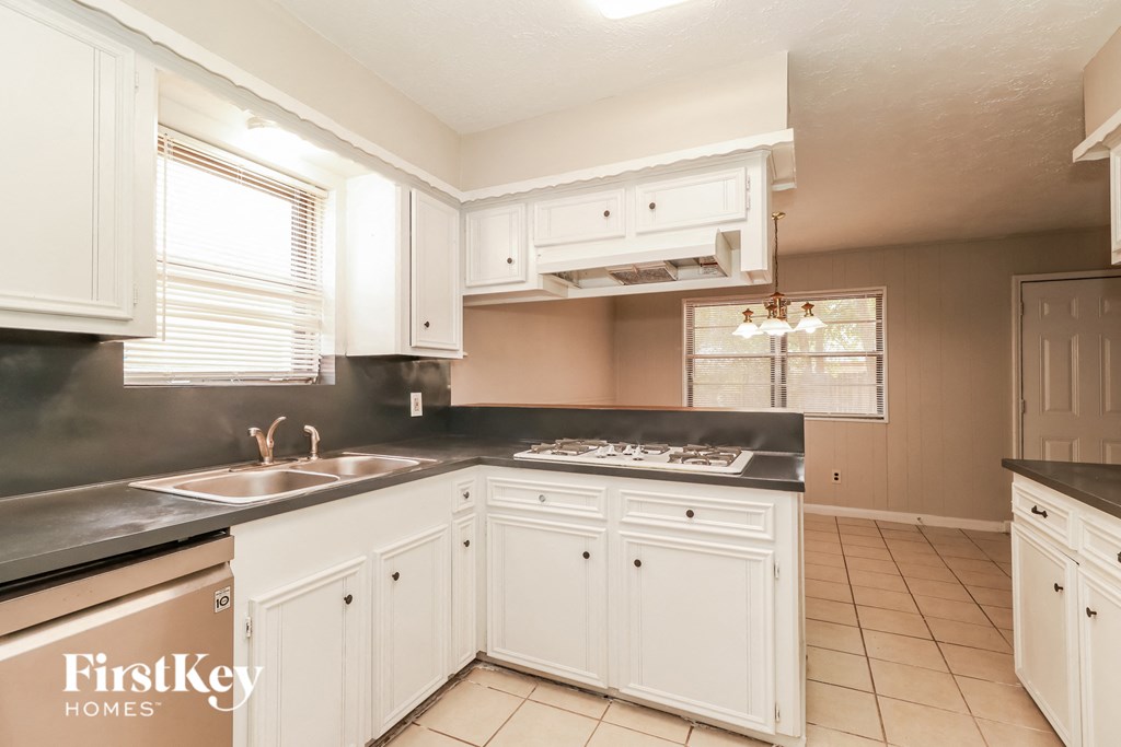 a kitchen with white cabinets and black counter tops