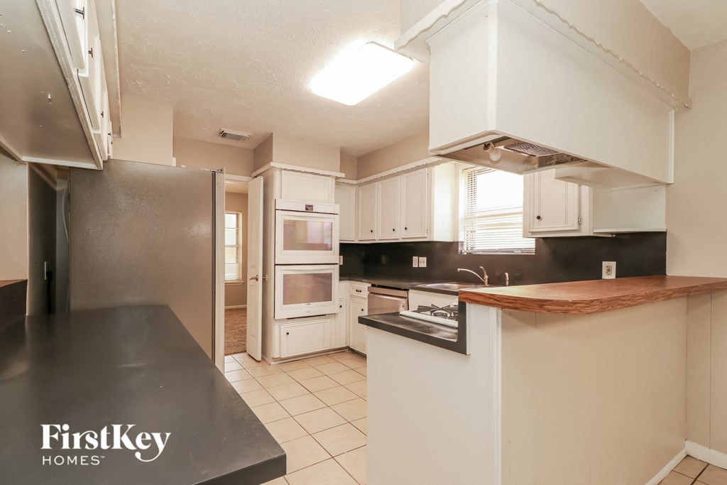 a kitchen with white cabinets and a black counter top