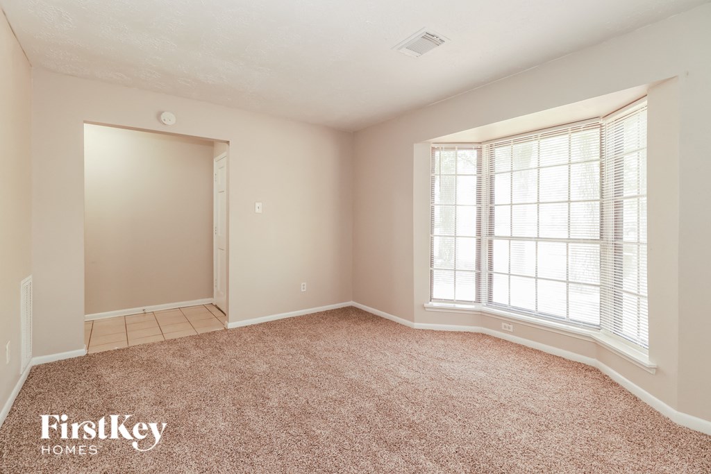 a bedroom with a large window and a carpeted floor