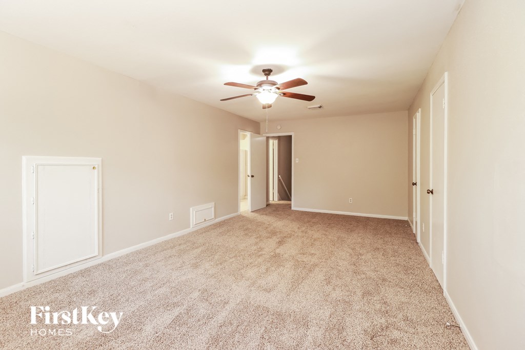 a spacious living room with carpet and a ceiling fan