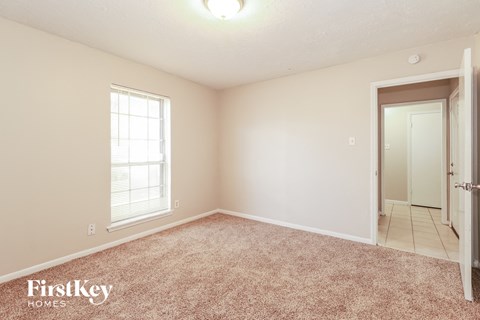 a bedroom with carpet and a door to a bathroom