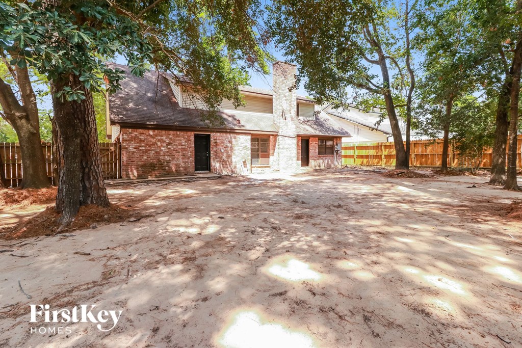 a brick house with a fenced yard and trees