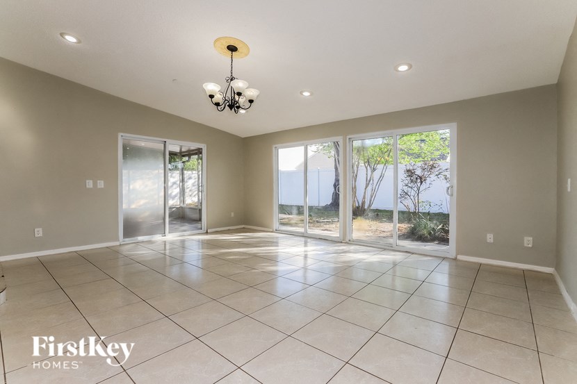 an empty living room with windows and a chandelier
