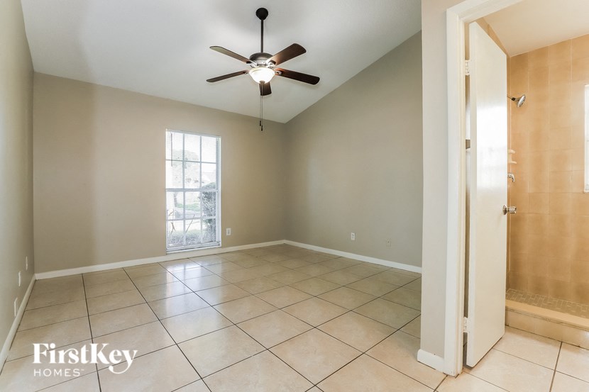 an empty living room with a ceiling fan and tiled floor