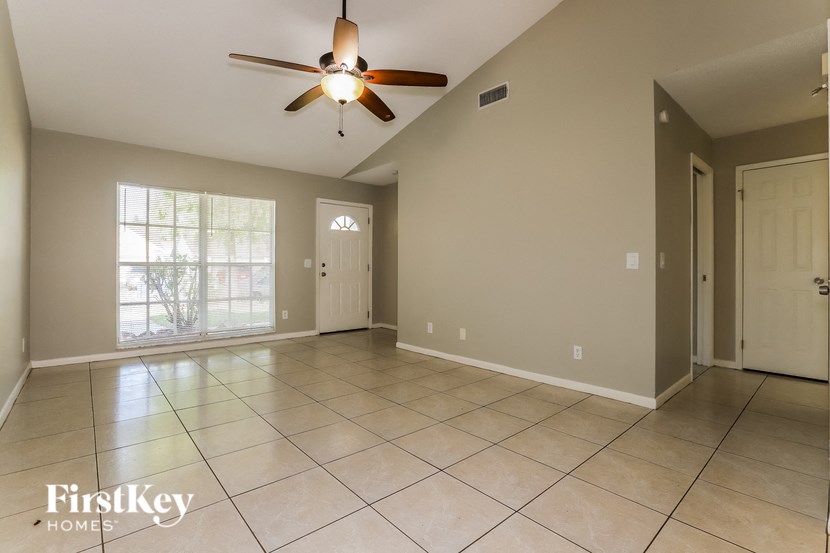 an empty living room with tile flooring and a ceiling fan