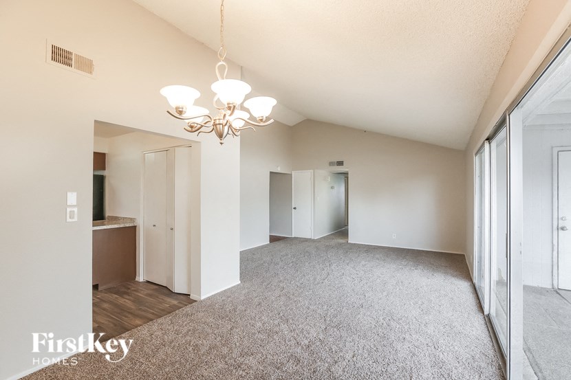 an empty living room and dining room with a chandelier