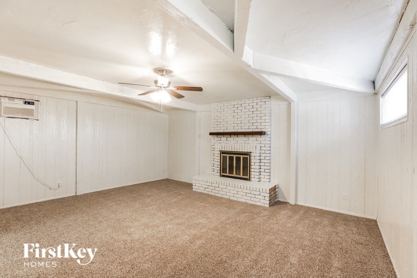 a living room with a brick fireplace and a ceiling fan