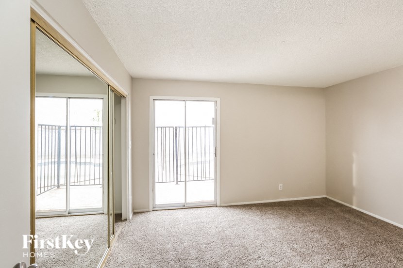 an empty living room with a sliding glass door to a balcony