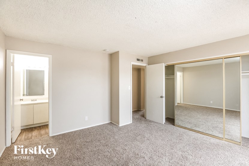 an empty bedroom with mirrored closet doors and carpeting