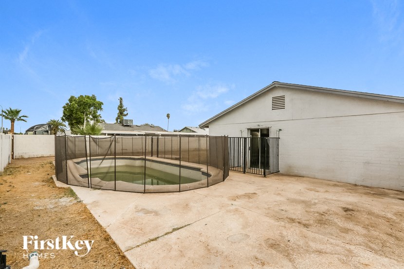 the backyard of a house with a pool behind a fence