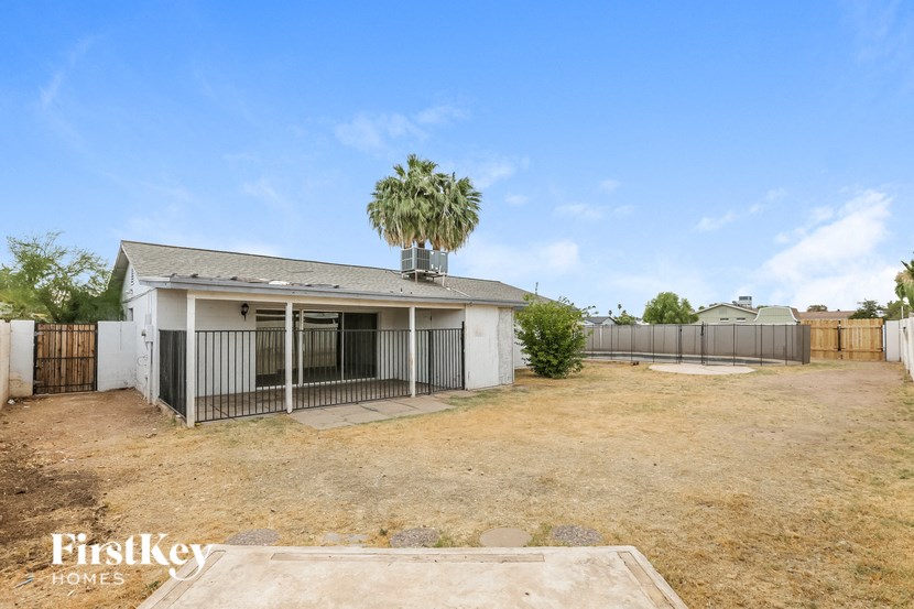 a house with a yard and a fence and palm trees