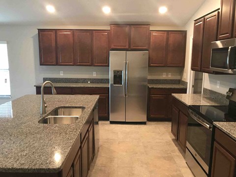 a kitchen with granite counter tops and a stainless steel refrigerator