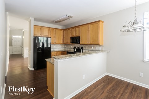 A kitchen with wooden cabinets and a black fridge.