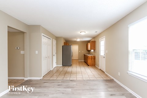 A spacious, empty room with a refrigerator in the middle.