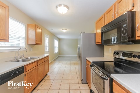 A kitchen with wooden cabinets and a black fridge.