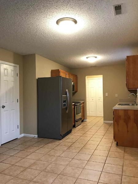 A kitchen with a black refrigerator and wooden cabinets.