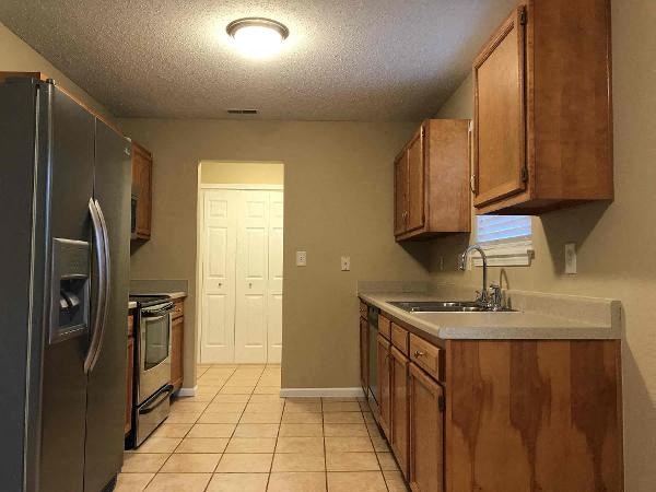 A kitchen with a refrigerator, oven, and sink.