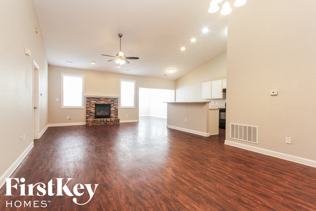 A spacious living room with wood flooring and a fireplace.