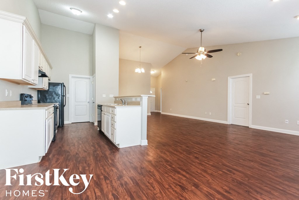 A spacious kitchen and living room with wooden floors and white walls.