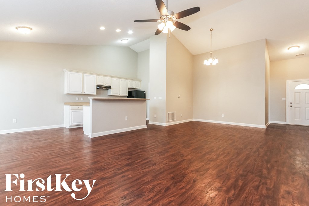 A spacious room with wooden floors and a ceiling fan.