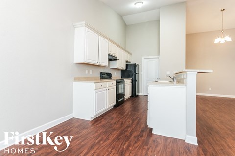 A kitchen with white cabinets and a wooden floor.