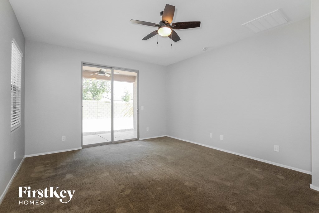 an empty living room with a ceiling fan and a door to a patio