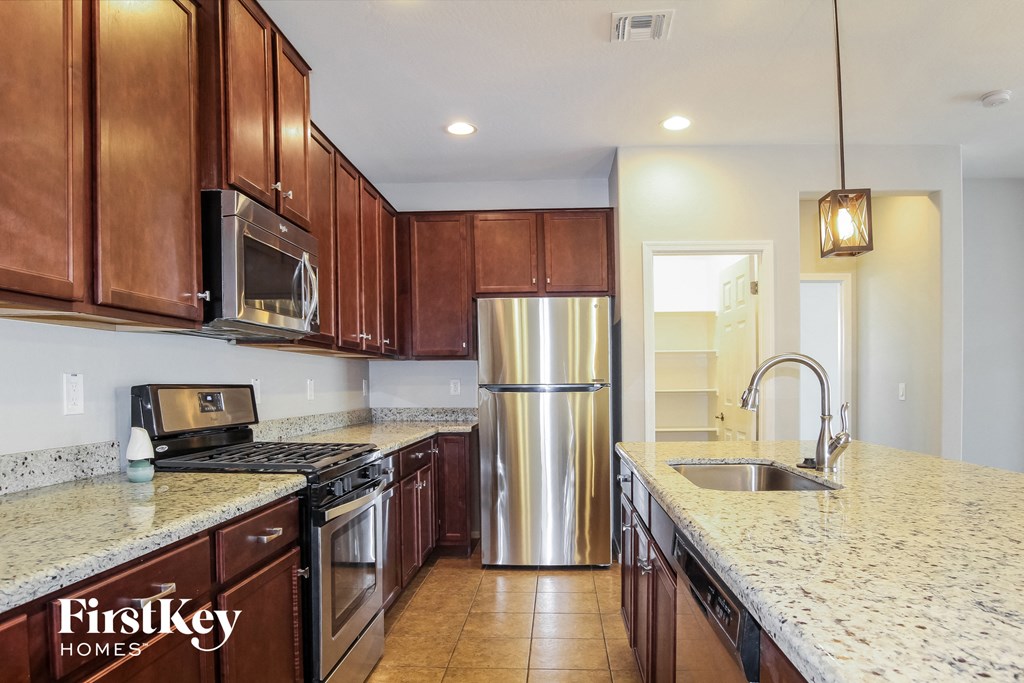 a kitchen with granite counter tops and a stainless steel refrigerator