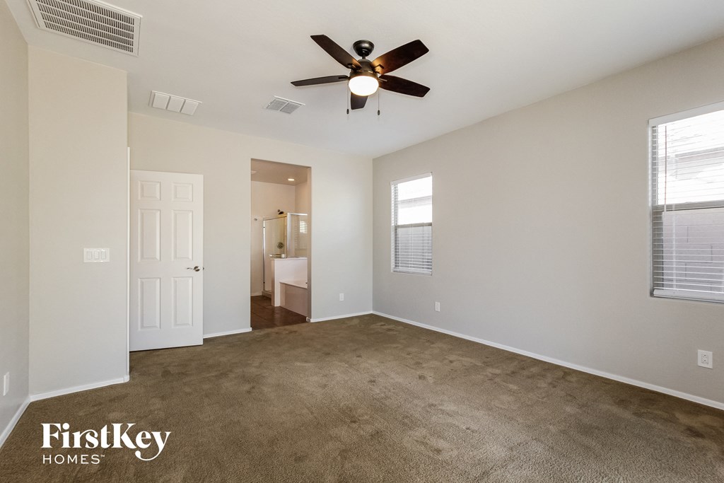an empty living room with carpet and a ceiling fan