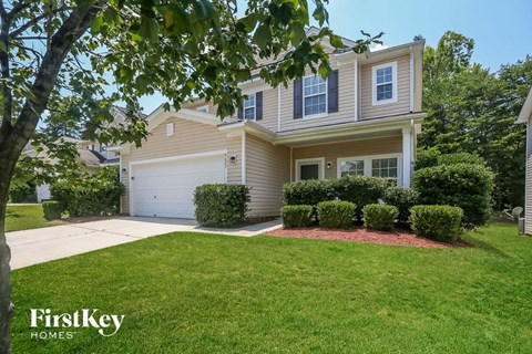 A house with a garage and a tree in front of it.