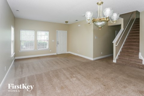 A spacious room with a staircase and a chandelier.