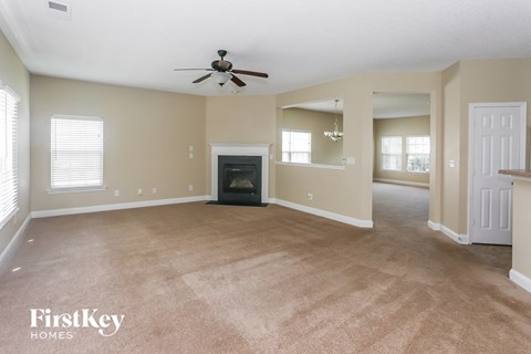 A spacious living room with a fireplace and a ceiling fan.